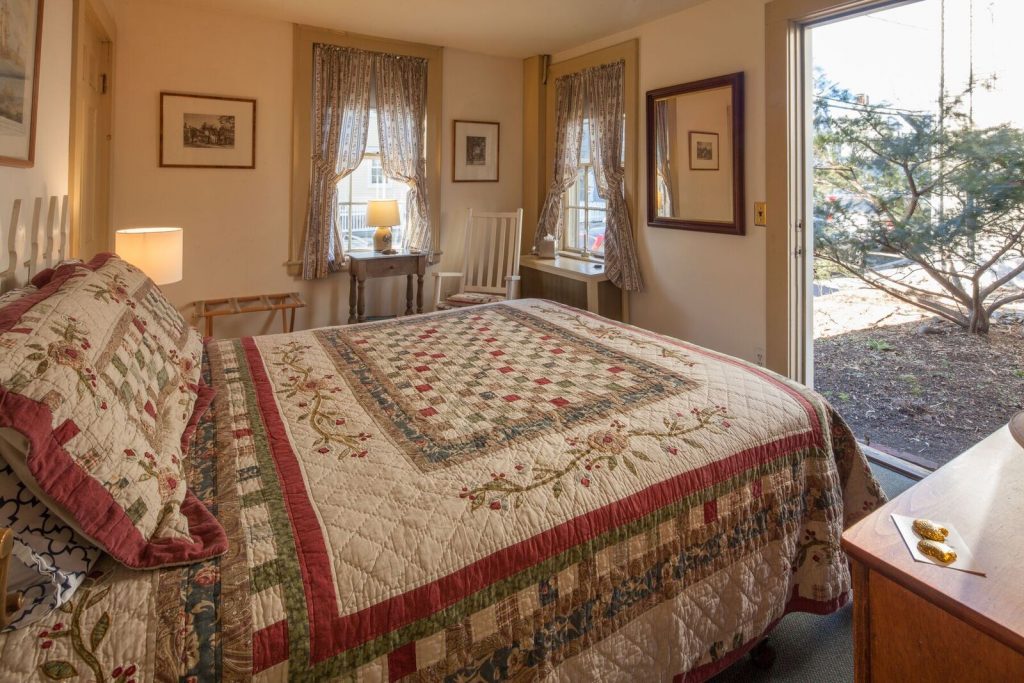 The Deck Room, overlooking part of the garden, is located on the first floor. It features a queen size bed and shares a bath with the Path Room. Marblehead art and artifacts decorate the Deck Room as well as walls throughout the B&B.